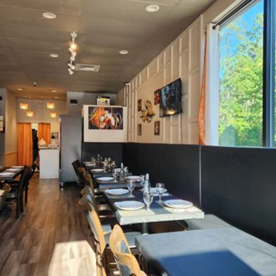 Interior of Spice Grill Indian Cuisine, featuring set tables, wooden floors, and a large window.
